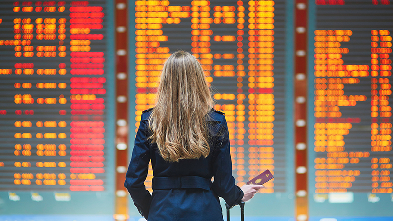 A woman looking at the flight status board at an airport
